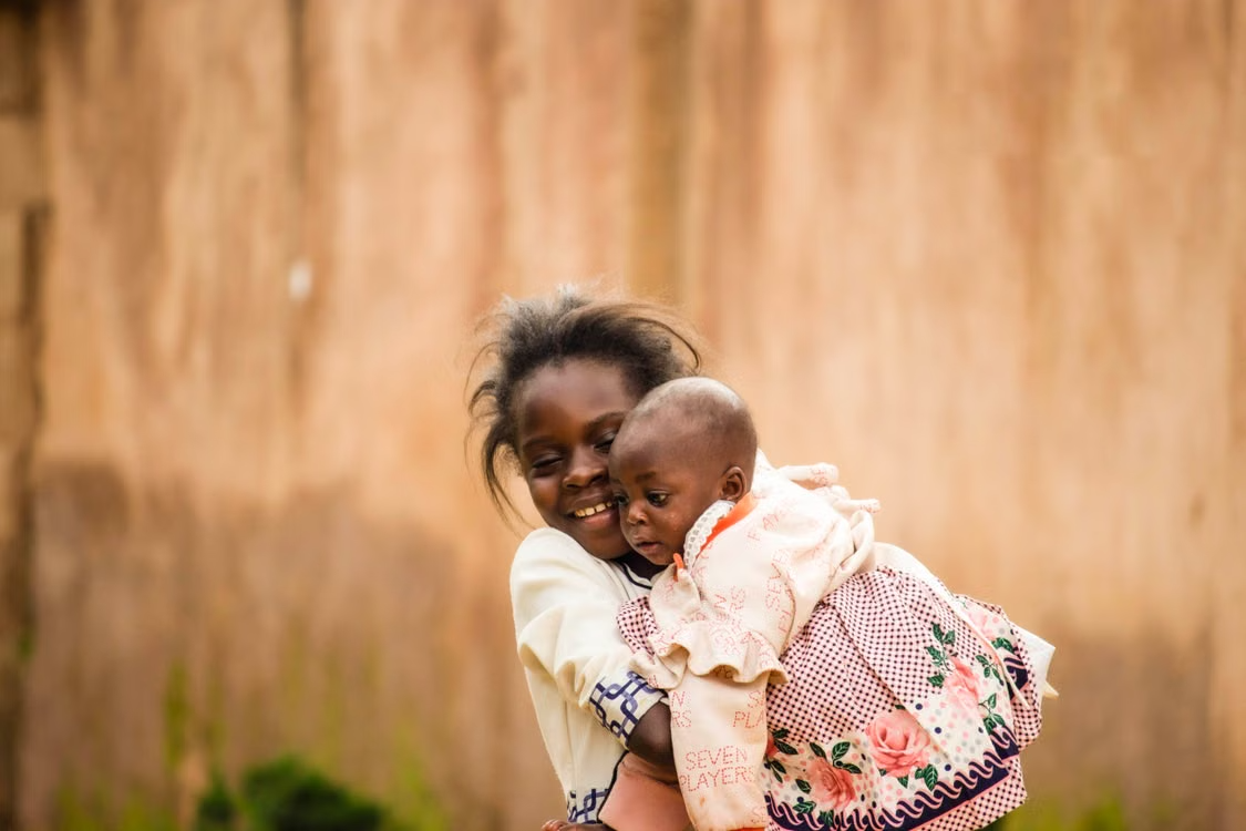 A young girl holding a baby